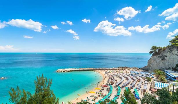 Crowded beach, turquoise sea, blue sky, lively and summery atmosphere.