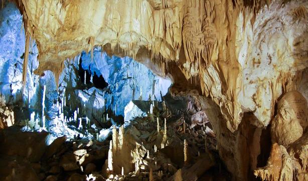 Stalactites and stalagmites dance in a lit cave, creating a mystical atmosphere.