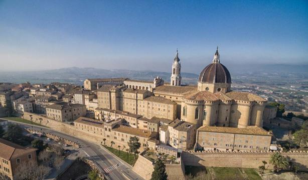 Aerial view of a majestic basilica in a rolling hillside landscape.